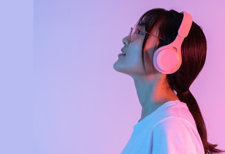 Woman listening to headphones on pink and lilac background